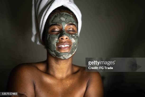 young woman using a facial mask - klei stockfoto's en -beelden