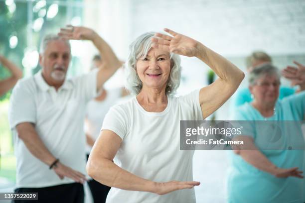 seniors indoor tai chi class - tai chi stock pictures, royalty-free photos & images