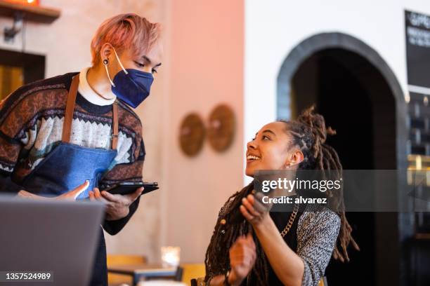 woman at cafe showing her digital vaccine certificate to waiter - coronavirus restaurant stock pictures, royalty-free photos & images