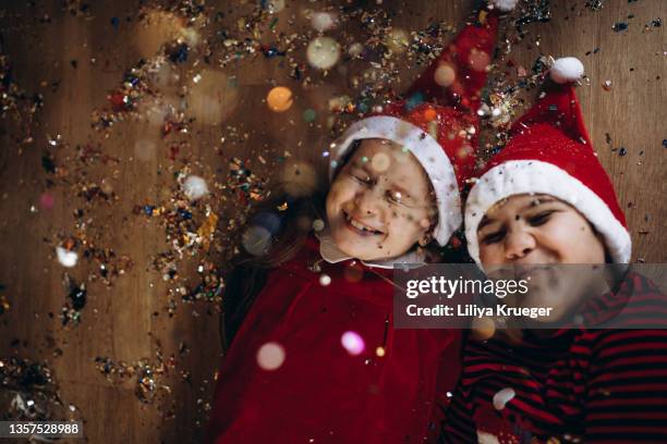 beautiful boy and girl lie under falling glittering confetti. - sparkle children stock pictures, royalty-free photos & images