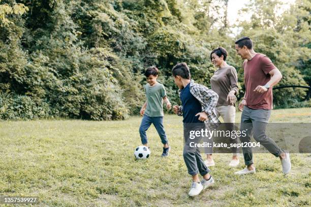 familia corriendo en el parque con balón de fútbol - playing football fotografías e imágenes de stock