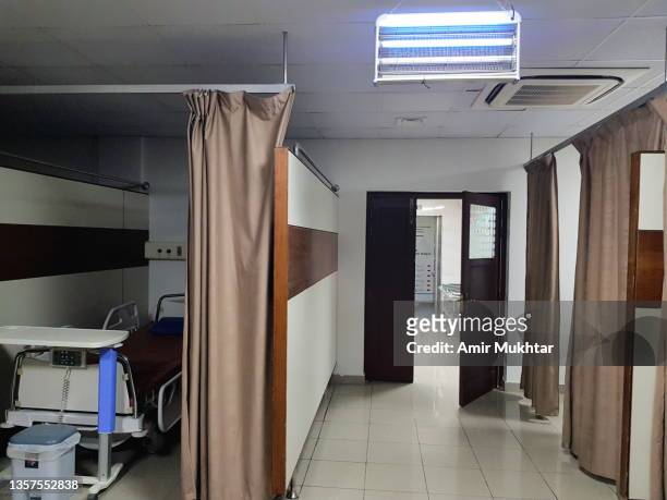 hanging illuminated fluorescent light on ceiling in a hospital ward with hospital patient bed. - asta per le tende foto e immagini stock