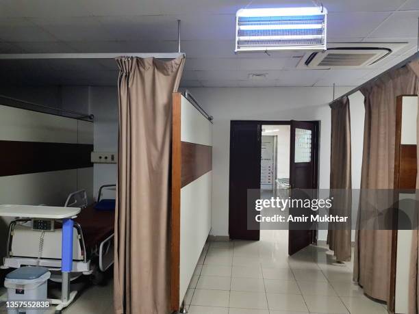 hanging illuminated fluorescent light on ceiling in a hospital ward with hospital patient bed. - カーテンレール ストックフォトと画像