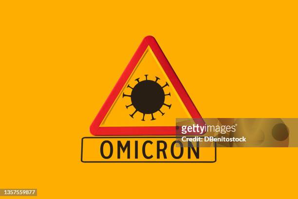 red and yellow danger road sign with coronavirus and omicron variant poster, on yellow background. concept of covid-19 pandemic, coronavirus, epidemic. - omicron photos et images de collection