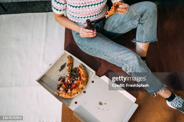 uma mulher irreconhecível comendo pizza e bebendo cerveja enquanto senta no chão - drinks carton - fotografias e filmes do acervo