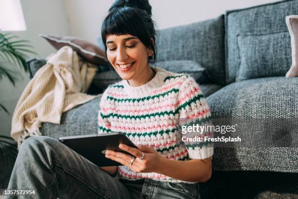 a beautiful woman holding her tablet and watching a funny podcast - surprised woman looking at tablet stock pictures, royalty-free photos & images