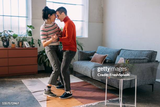 ein glückliches paar tanzt im wohnzimmer - living room young couple stock-fotos und bilder