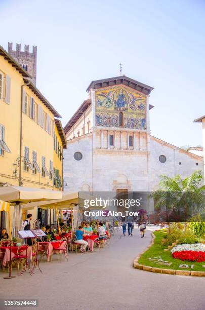 city street with basilica of san frediano lucca, italy - lucca italy stock pictures, royalty-free photos & images