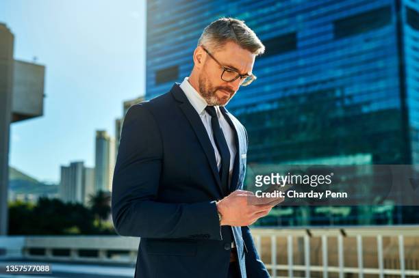 shot of a mature business man using his cellphone outside - businessman imagens e fotografias de stock