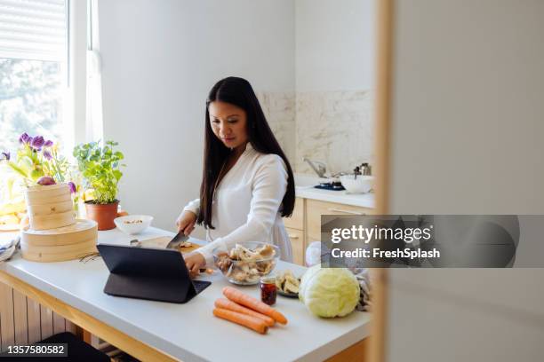 beautiful woman using digital tablet in her kitchen - mushroom types stockfoto's en -beelden