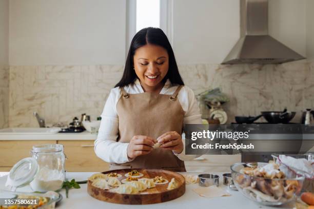 happy woman preparing healthy meal in her kitchen - chinese dumpling stock pictures, royalty-free photos & images