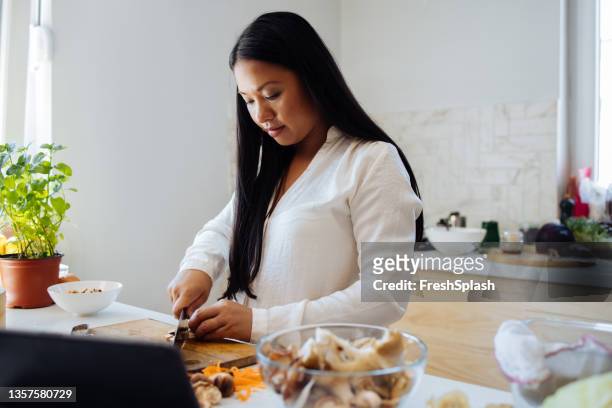 beautiful woman using digital tablet in her kitchen - mushroom types stockfoto's en -beelden