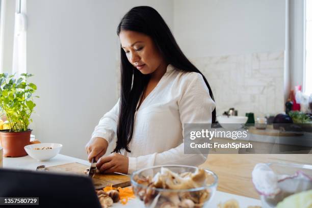 beautiful woman using digital tablet in her kitchen - cooked mushrooms stock pictures, royalty-free photos & images