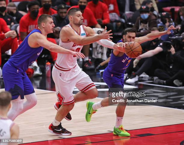 Nikola Jokic and Facundo Campazzo of the Denver Nuggets chase a loose ball with Nikola Vucevic of the Chicago Bulls at the United Center on December...