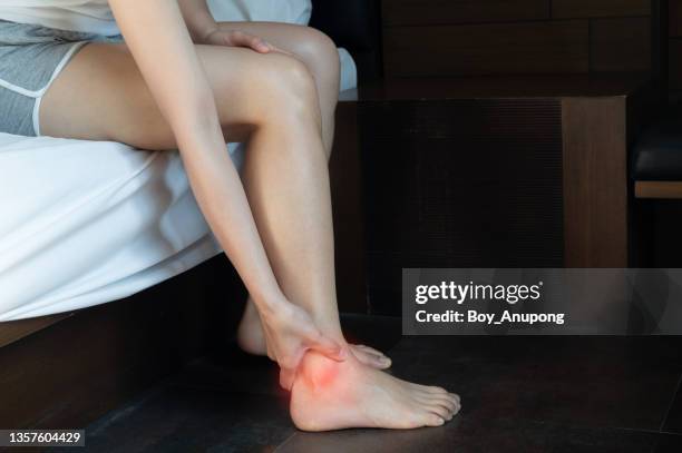 cropped shot of woman hand touching her ankle caused of suffering from ankle pain. - ankle stock pictures, royalty-free photos & images