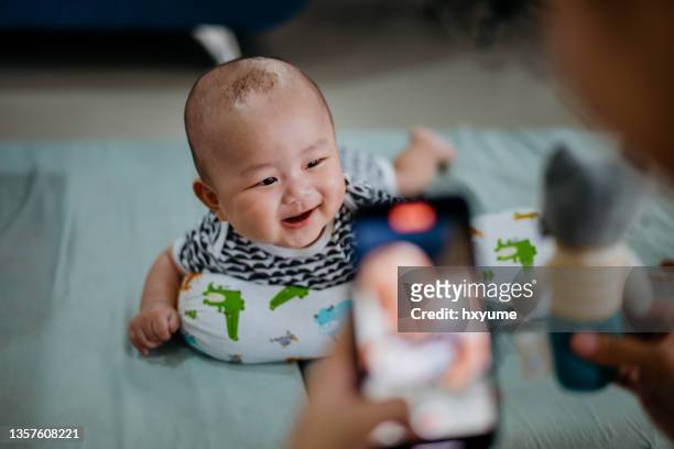 mother capturing a photo of her baby during tummy time - bolster stock pictures, royalty-free photos & images