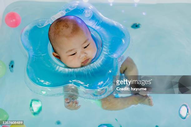 baby boy learning to swim in bathtub - drijven stockfoto's en -beelden