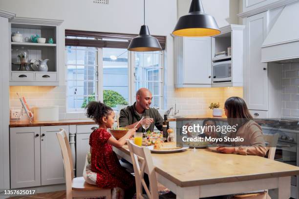 shot of a young family enjoying a meal together - at home stock pictures, royalty-free photos & images