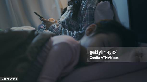 mother using smart phone while daughter sleeping at night. - baby being held stockfoto's en -beelden