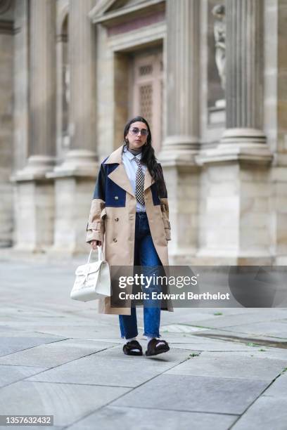 Gabriella Berdugo wears sunglasses from Gucci, gold earrings, a brown ribbed wool turtleneck pullover, a white shirt from Wrangler, a black and white...