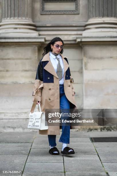 Gabriella Berdugo wears sunglasses from Gucci, gold earrings, a brown ribbed wool turtleneck pullover, a white shirt from Wrangler, a black and white...