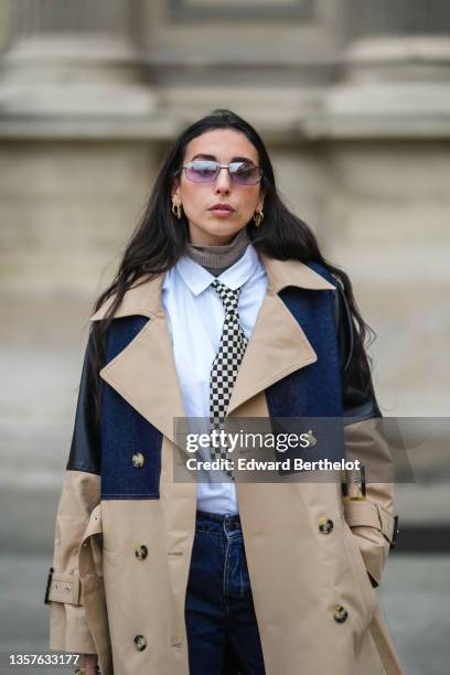 Gabriella Berdugo wears sunglasses from Gucci, gold earrings, a brown ribbed wool turtleneck pullover, a white shirt from Wrangler, a black and white...