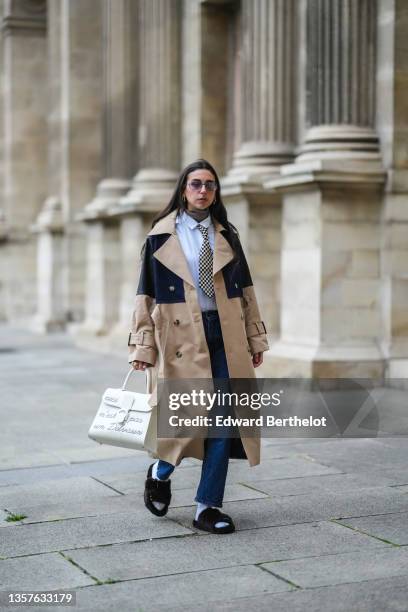 Gabriella Berdugo wears sunglasses from Gucci, gold earrings, a brown ribbed wool turtleneck pullover, a white shirt from Wrangler, a black and white...