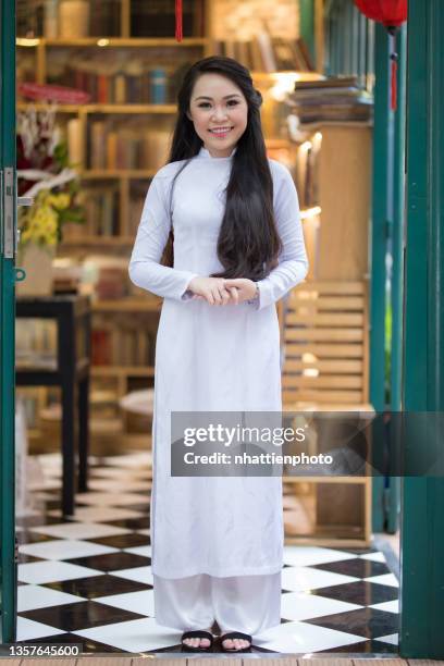 happy asia giovane receptionist femminile in vietnamita tradizionale ao dai stand di fronte alla porta - vietnamese ethnicity foto e immagini stock