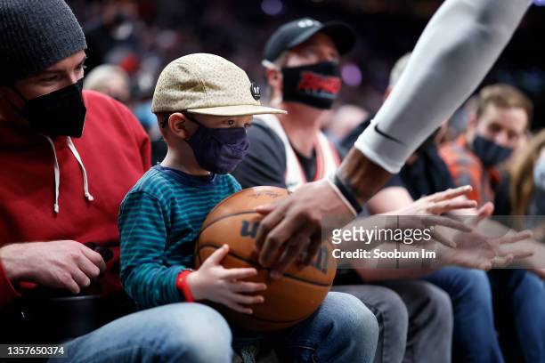 Marcus Morris Sr. # 8 of the Los Angeles Clippers hands a ball to a young fan during the first half against the Portland Trail Blazers at Moda Center...