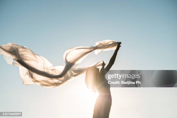 young woman stand at meadow and holding plastic translucent cellophane fluttering in the wind - white trash stock-fotos und bilder