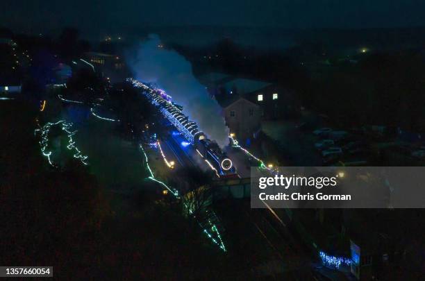 An aerial view of a steam train illuminated on the Watercress Line on December 4,2021 at Ropley, England. The line gained its popular name in the...