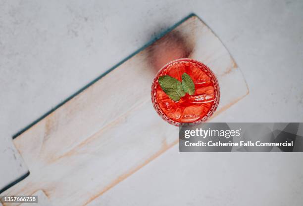 simple top down image of a berry flavoured drink on a wooden board, garnished with mint and ice. space for copy. - aronia berry stock-fotos und bilder