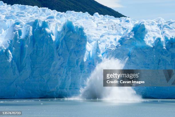 ice calving off of the perito moreno glacier. - internationaal monument stockfoto's en -beelden