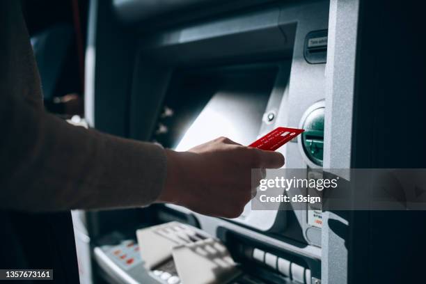 close up of young woman inserting her bank card into automatic cash machine in the city. withdrawing money, paying bills, checking account balances, transferring money. privacy protection, internet and mobile security concept - sportello bancomat foto e immagini stock