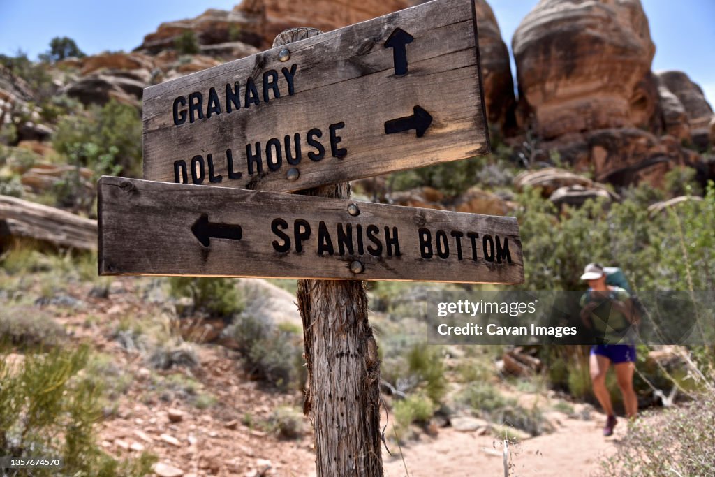 Trail sign directing female hiker in Canyonlands National Park, Moab, Utah, USA