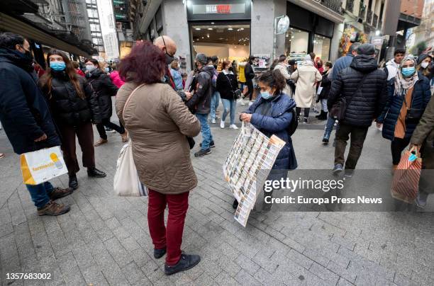 Woman buys a Christmas lottery ticket from a street vendor with less than three weeks to go until the Extraordinary Christmas Lottery Draw on...