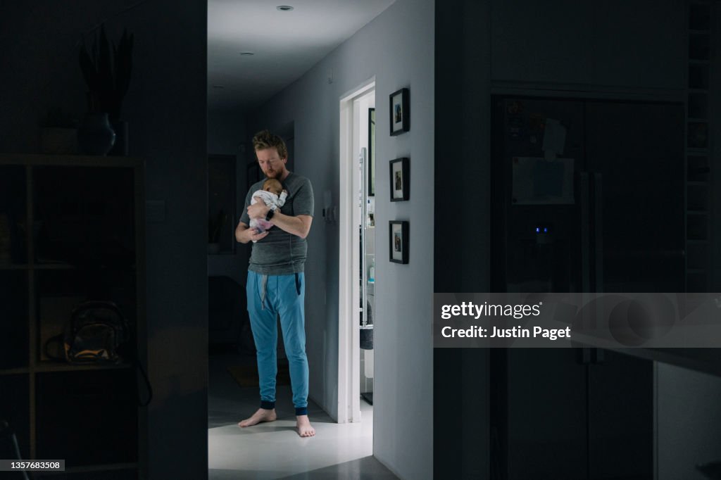 Mature man trying to get his newborn baby to sleep late at night