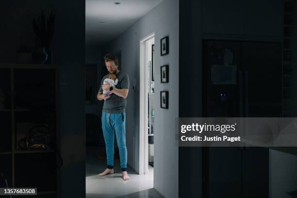 mature man trying to get his newborn baby to sleep late at night - baby bottle foto e immagini stock