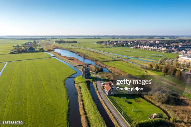 typical dutch polder landscape with windmill and dutch village - netherlands stock pictures, royalty-free photos & images