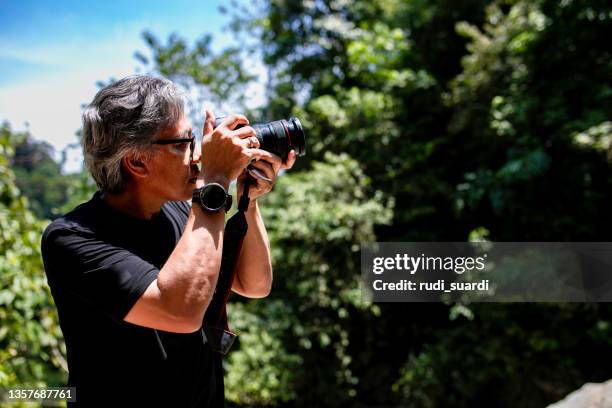 senior asian photographer standing in jungle - senior photographer stock pictures, royalty-free photos & images