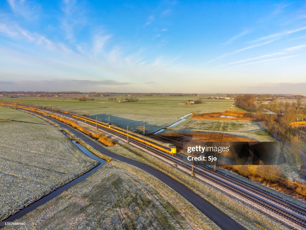 Train of the Dutch Railways NS driving through the countryside during winter