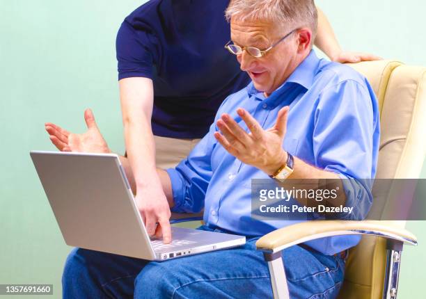 senior man receiving guidance on computer from young man - ominous computer stock pictures, royalty-free photos & images
