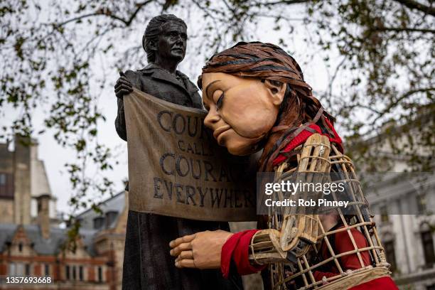 Little Amal hugs the statue of suffragist Millicent Fawcett in Parliament Square on December 07, 2021 in London, England. The groups behind Little...