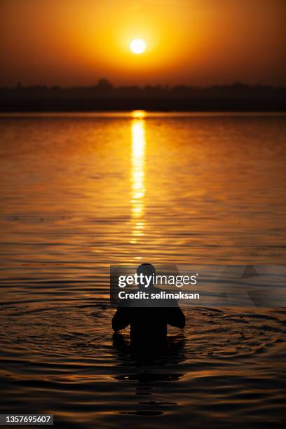 hindu man praying by taking bath in ganges river varanasi, india - ganges river stock pictures, royalty-free photos & images