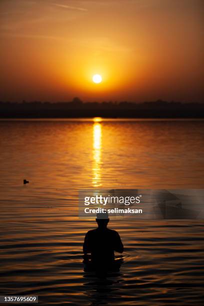 hindu man praying by taking bath in ganges river varanasi, india - river bathing stock pictures, royalty-free photos & images