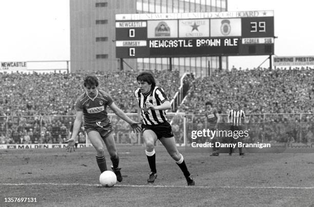 Newcastle striker Peter Beardsley runs at the Grimsby defence as the Gallowgate Electronic scoreboard advertises Newcastle Brown Ale during a 0-1...