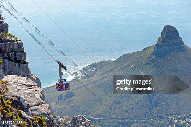 cable car travelling with lion's head in background from table mountain, cape town, cape province, south africa. - cape town cable car stock pictures, royalty-free photos & images