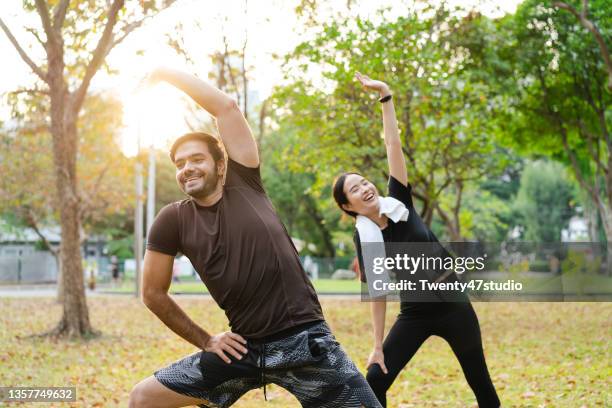 multiracial couple exercised in the park stretching body - couple exercising 30s stock pictures, royalty-free photos & images