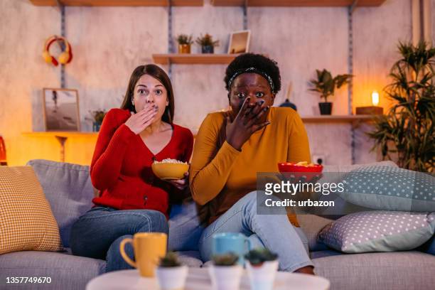 two women watching horror movie at home - binge watching stock pictures, royalty-free photos & images