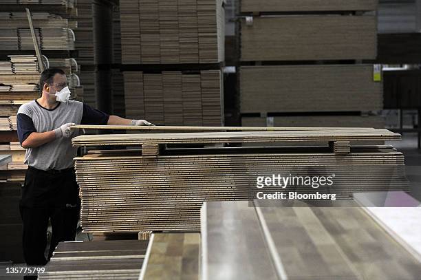 An employee arranges a block of wood laminate flooring after manufacture at the Tarkett Group factory in Backa Palanka, Serbia, on Tuesday, Dec. 13,...